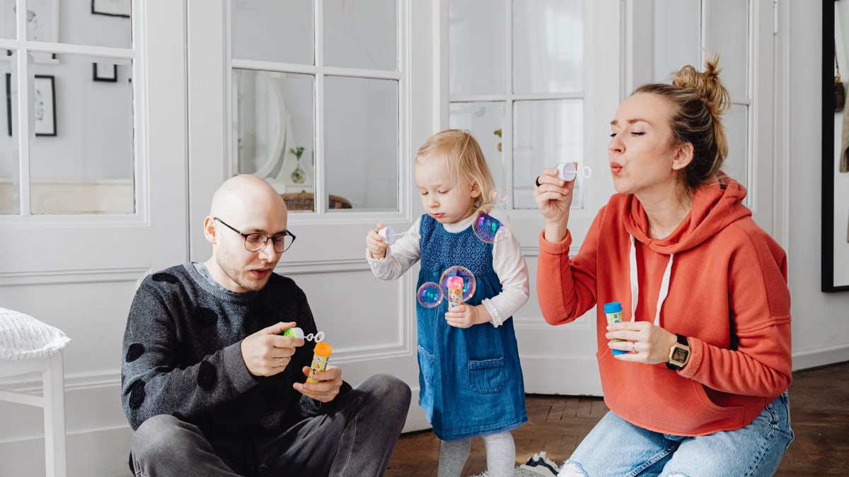 Family enjoying quality time blowing bubbles indoors, capturing joyful moments.